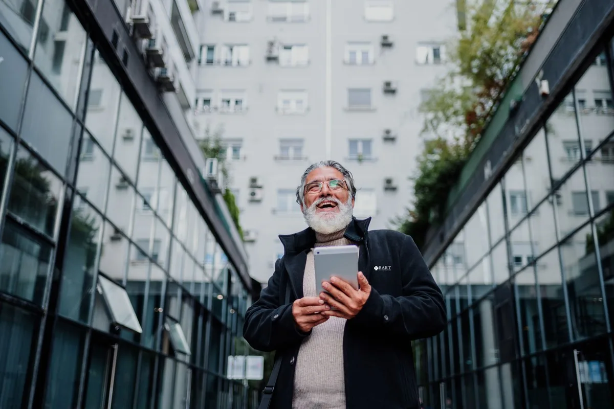 Huismeester met tablet tussen een woonflat en een kantoorpand